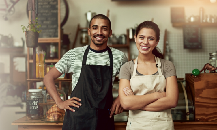 um homem e uma mulher de avental sorridentes na frente de um balcão 