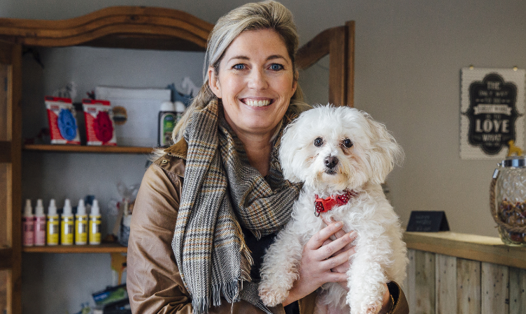 mulher loira sorridente segurando um cachorro peludo branco