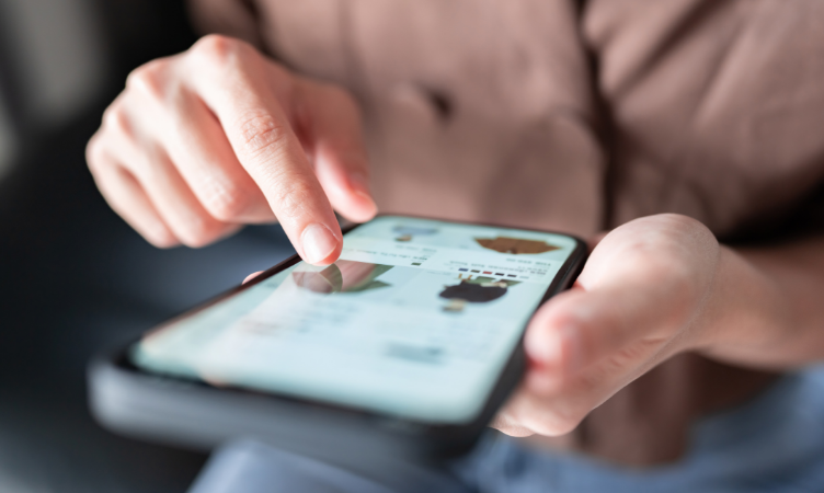 Imagem de um celular com uma mão de uma pessoa deslizando a tela navegando em um e-commerce