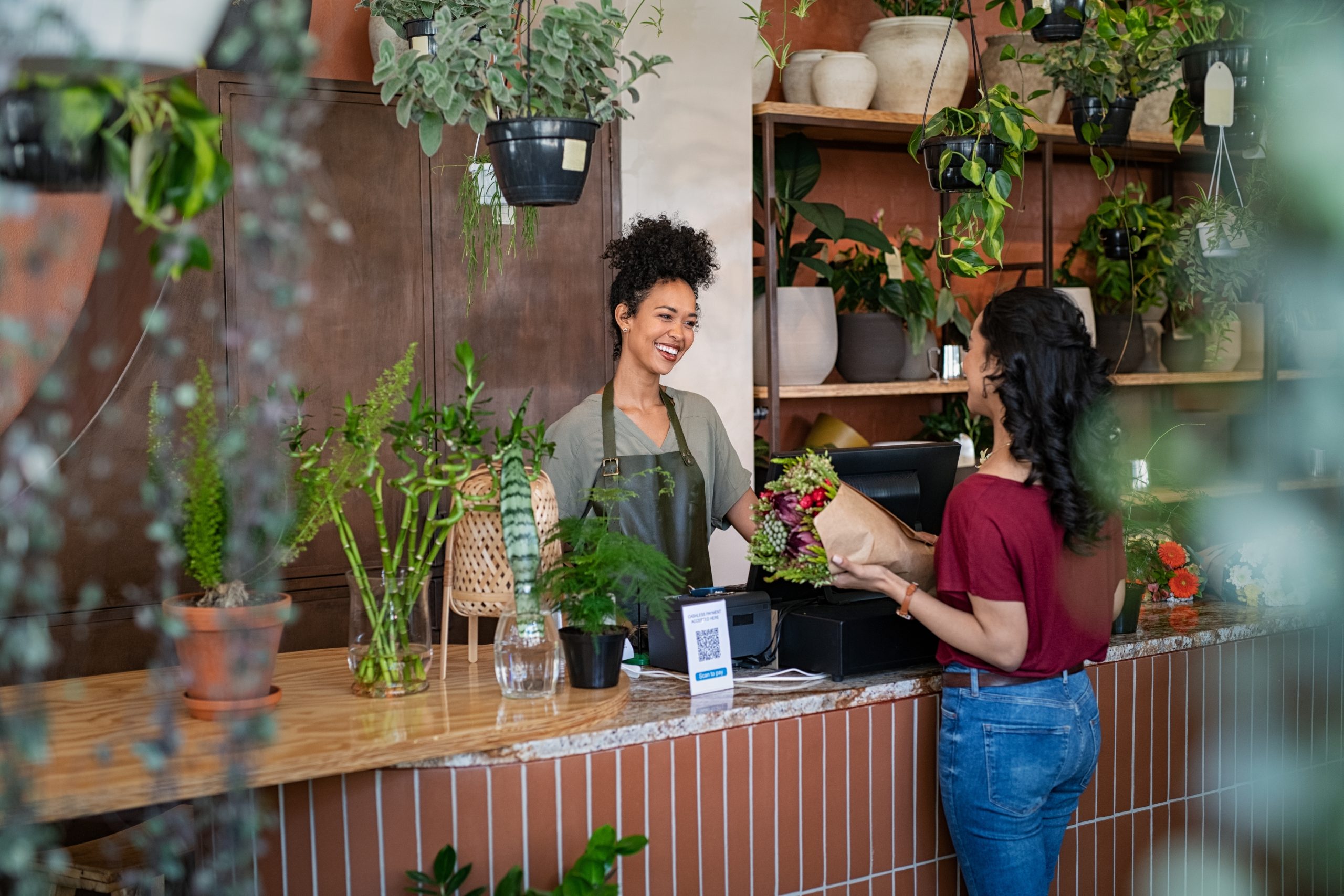 relacionamento com cliente: mulher no caixa atendendo outra mulher em uma floricultura