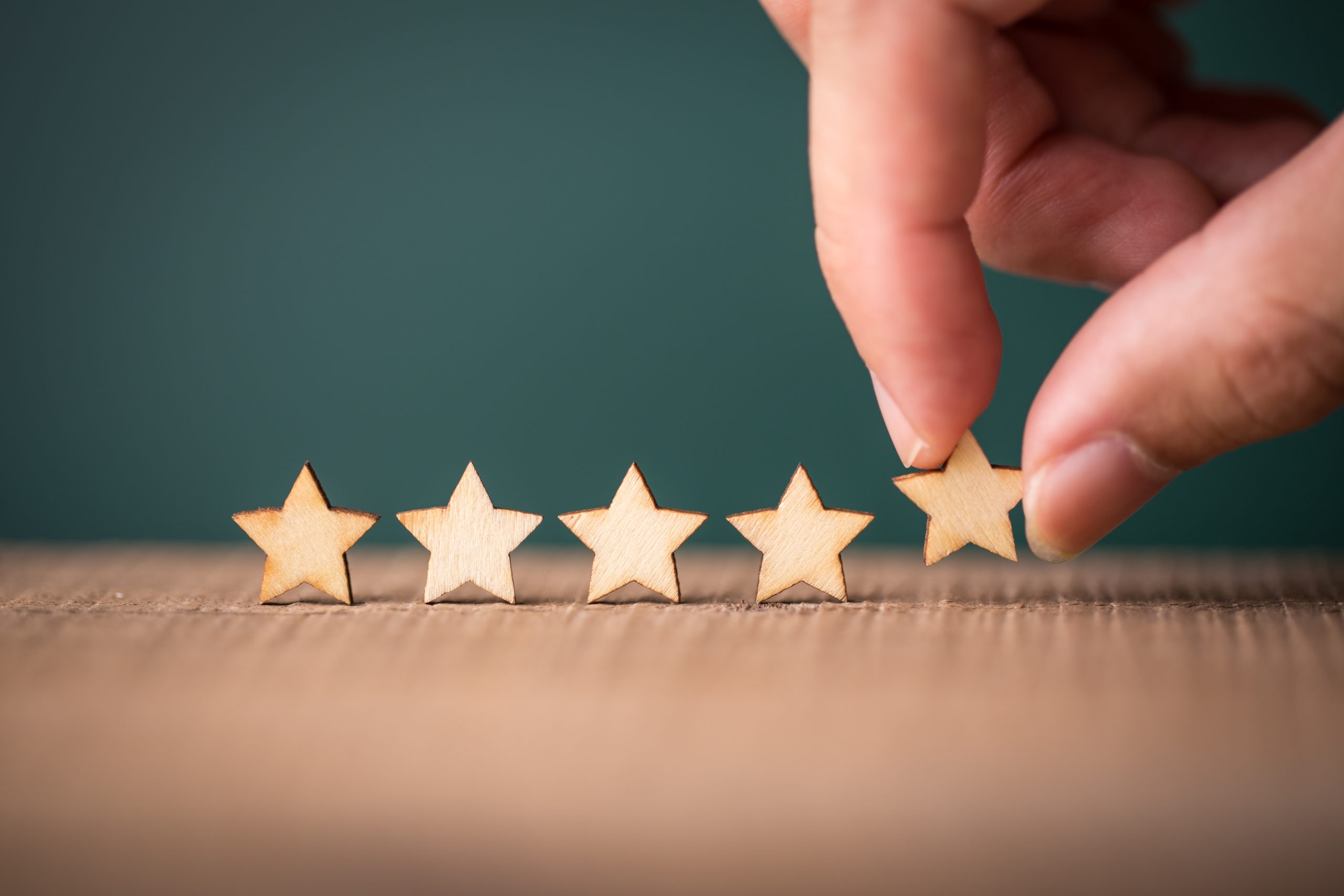mão colocando estrelas de madeiras em fila na mesa - ciclo de vida do cliente