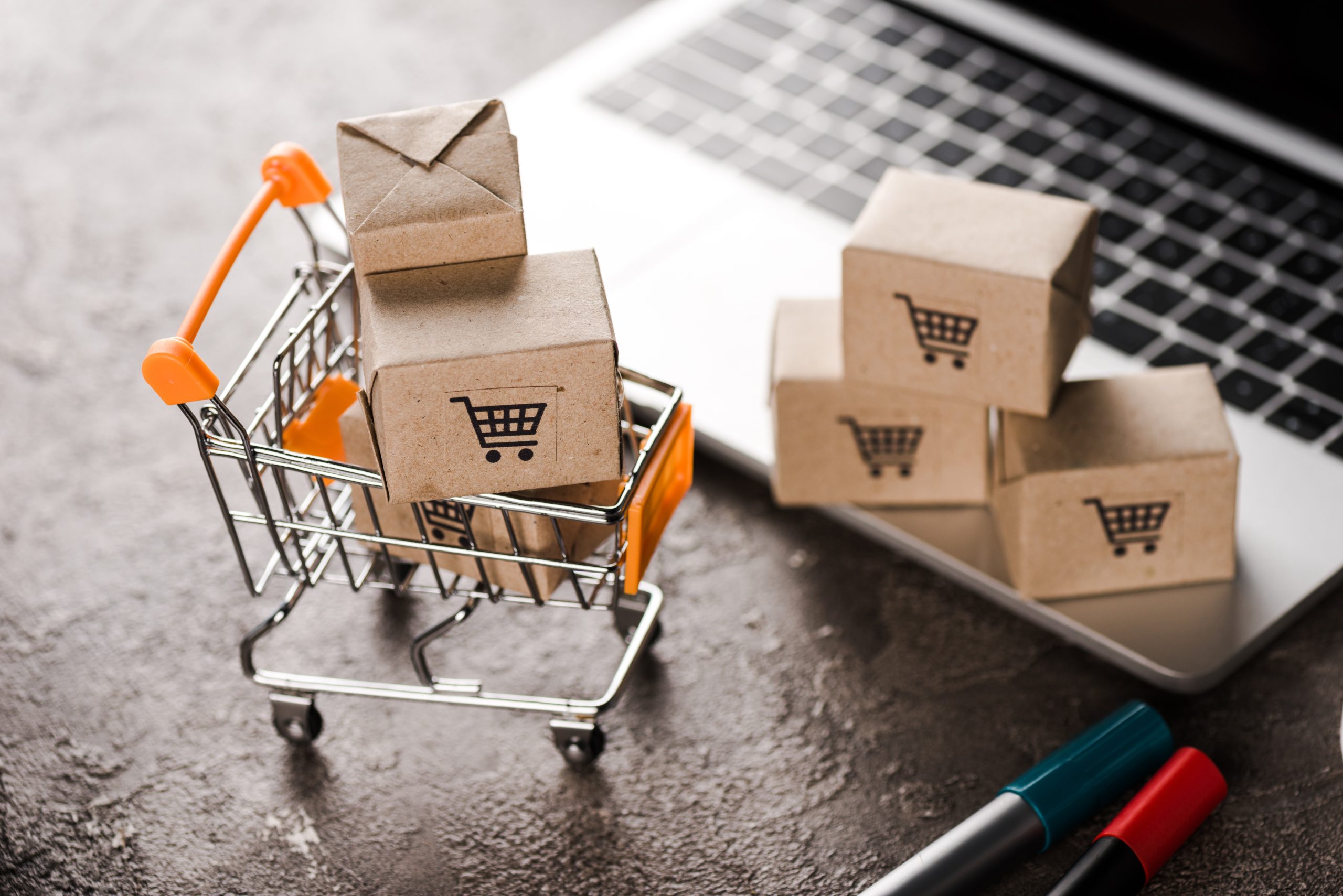 vendas online no RS - mini carrinho cheio de caixas de compras em frente ao teclado de um notebook.
